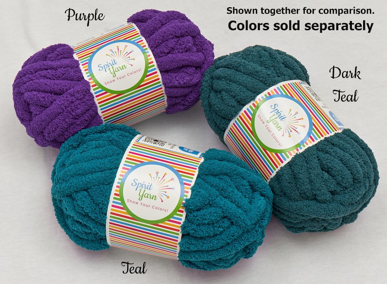 May include: Three skeins of yarn in purple and teal colors. The yarn is soft and fluffy, and it is perfect for crocheting or knitting. The yarn is labeled "Spirit Yarn" and "Show Your Colors!"