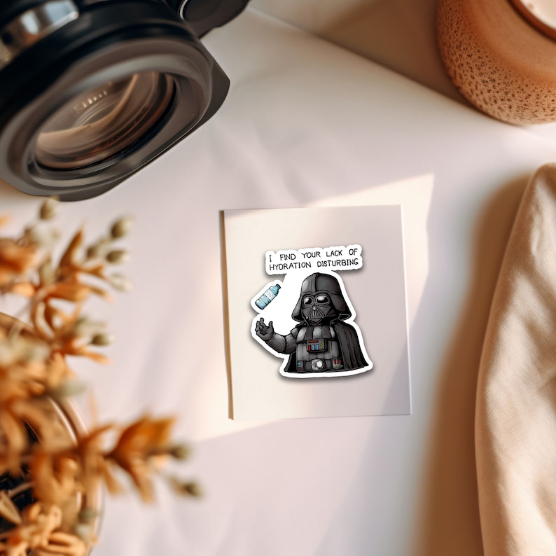 May include: A white card with a cartoon image of Darth Vader holding a water bottle. The text on the card reads "I find your lack of hydration disturbing."