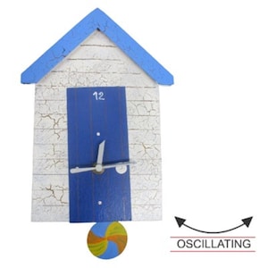 May include: A white and blue beach hut shaped clock with a blue door and a beach ball pendulum. The clock face has a white background with black numbers and hands. The clock is oscillating.