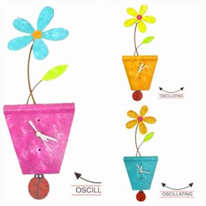 May include: A colorful flower clock with a ladybug pendulum. The clock is in a pot with a pink, orange, or blue finish. The flower is yellow with a pink center. The clock face is white with black hands. The pendulum is a red ladybug with black spots. The clock is oscillating.