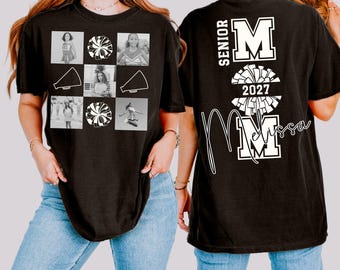 May include: Black t-shirt featuring a collage of cheerleading images and a pom-pom design. The front displays photos and cheerleading graphics. The back has "SENIOR" and "MOM 2027" with a name in script. A comfortable, casual tee.