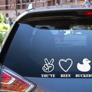 May include: A white vinyl sticker with a peace sign, heart, and rubber ducky graphic. The sticker says "You've Been Ducked!"