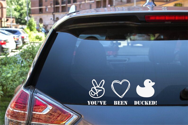 May include: A white vinyl sticker with a peace sign, heart, and rubber ducky graphic. The sticker says "You've Been Ducked!"