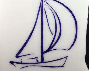 May include: A white ceramic tile with a blue line drawing of a sailboat. The tile is signed "IAN" in the bottom right corner.