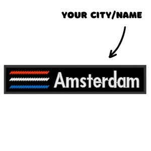 May include: Black and white embroidered patch with the text "Amsterdam" in white and a red, white, and blue striped design. The text "YOUR CITY/NAME" is written above the patch.