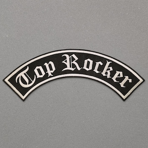 Könnte beinhalten: Schwarzer, gebogener Aufnäher mit dem Schriftzug "Top Rocker" in weißer, gotischer Schrift. Der Aufnäher hat einen weißen Rand und ist zum Aufnähen auf Kleidung bestimmt.