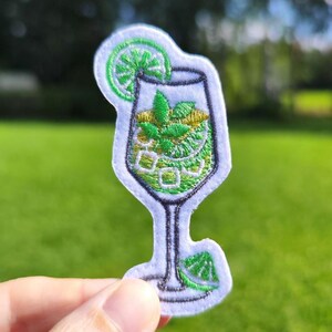 May include: Embroidered patch featuring a mojito cocktail design. The patch showcases a green and white cocktail glass with a lime slice, ice cubes, and mint leaves. The patch is on a white background with a black outline.
