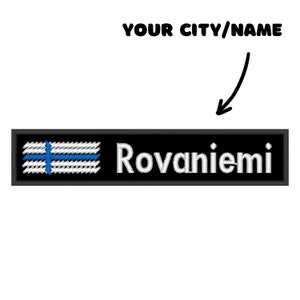 Op de afbeelding: Zwarte en witte geborduurde patch met een blauwe Finse vlag en de tekst "Rovaniemi" in wit.