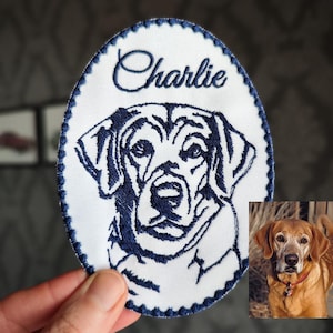 Op de afbeelding: Witte ovale geborduurde patch met een blauwe rand. De patch heeft een zwart-wit geborduurde afbeelding van een hondenkop met de naam "Charlie" erboven.