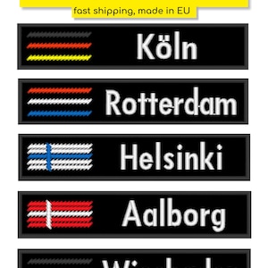 Könnte beinhalten: Schwarze rechteckige Aufnäher mit gestickten Städtenamen und Flaggenmotiven. Zu den Städten gehören Köln, Rotterdam, Helsinki, Aalborg und Wiesbaden. Das obere Banner lautet "ANY TEXT & FLAG".
