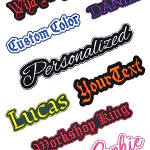 Può includere: Una collezione di toppe ricamate in vari colori e caratteri. Le toppe presentano parole e frasi come "Wild Heart", "Custom Color", "Personalized", "Your Text", "Lucas", "Workshop King", "Sophie" e "Daniel".