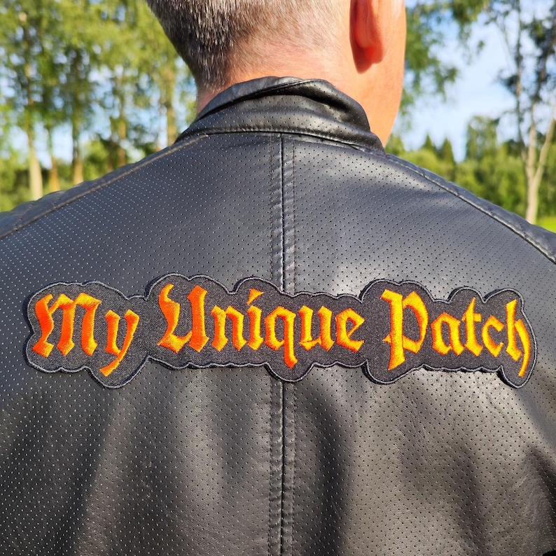 Puede incluir: Una chaqueta de cuero negra con un parche bordado en naranja y negro que dice "My Unique Patch".