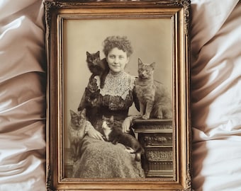 May include: Vintage framed photograph featuring a woman surrounded by five cats. The sepia-toned image shows the woman in a dress with lace detailing, with cats perched on her shoulders, lap, and a nearby surface. The frame is ornate with a gold finish.