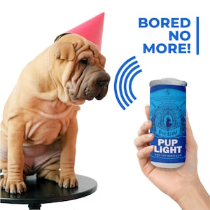 May include: A brown and white Shar-Pei dog wearing a pink party hat looks at a blue and white dog toy shaped like a can of beer. The can has the text "Pup Light Dog Toy Beer Can" on it. The text "Bored No More!" is written above the can.
