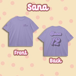 K&ouml;nnte beinhalten: Lilafarbenes T-Shirt mit "Twice" auf der Vorderseite und "Sana 12" auf der R&uuml;ckseite in einer Retro-Schrift.