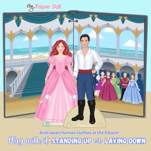 May include: A paper doll set featuring Ariel in a pink gown and Prince Eric in a white shirt and blue pants. The background depicts a palace scene with other characters. Text reads "My Paper Doll" and "Play with it STANDING UP or LAYING DOWN."