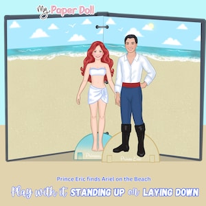 May include: A paper doll set featuring Ariel and Prince Eric on a beach scene. Ariel has red hair and a white top and skirt. Prince Eric wears a white shirt, blue pants, and black boots. The text reads "Prince Eric finds Ariel on the Beach."