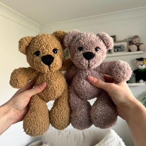 Op de afbeelding: Twee pluche teddyberen, &eacute;&eacute;n bruin en &eacute;&eacute;n mauve, worden getoond. De beren hebben zwarte knoopogen en gestikte neuzen. De beren zijn zacht en knuffelig. Ideaal als kinderspeelgoed of decoratie.