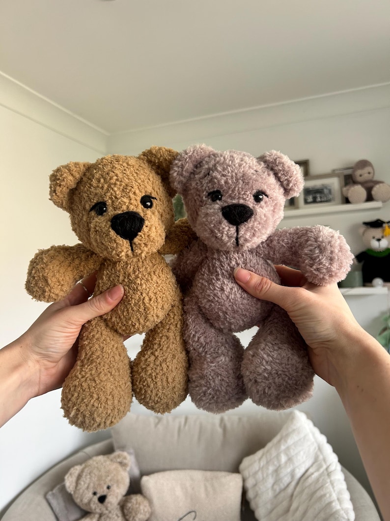 Op de afbeelding: Twee pluche teddyberen, &eacute;&eacute;n bruin en &eacute;&eacute;n mauve, worden getoond. De beren hebben zwarte knoopogen en gestikte neuzen. De beren zijn zacht en knuffelig. Ideaal als kinderspeelgoed of decoratie.