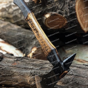 Pu&ograve; includere: Un'ascia nera e marrone con un manico di legno e una lama affilata. L'ascia &egrave; appoggiata su un tronco di legno.