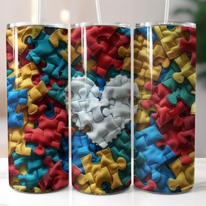 May include: A set of three stainless steel tumblers with a colorful puzzle piece design. The design features a heart shape made of white puzzle pieces, surrounded by red, yellow, blue, and teal puzzle pieces.