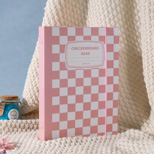 May include: Pink binder with a checkerboard pattern and the text "CHECKERBOARD BOOK" with the word "sweetcool" underneath.