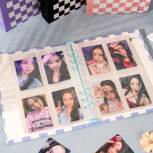 May include: A blue and white checkered photo album with clear plastic sleeves holding photos of a woman. The album has a blue ring binder.