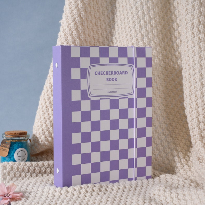 May include: Purple and white checkered binder with the text "Checkerboard Book" and "sweetcool" on the front.