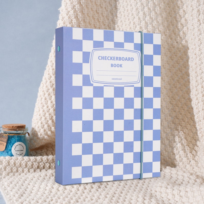 May include: A blue and white checkered binder with the text "CHECKERBOARD BOOK" and "sweetcool" on the front.