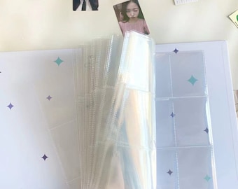 May include: A white photo album with clear plastic sleeves for holding photos. The album is open and the sleeves are filled with photos. The album has a blue and purple star pattern on the cover.