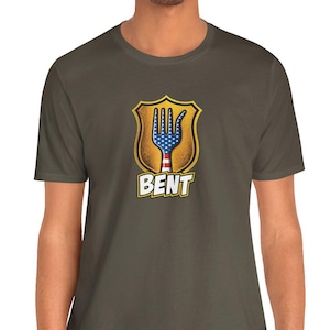 May include: A dark olive green t-shirt featuring a graphic of a fork shaped like a hand with a blue and white star-spangled pattern on the fingers and red and white stripes on the handle, enclosed in a gold shield with the word BENT below.