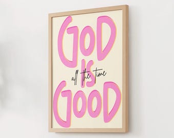 Può includere: Stampa artistica incorniciata con la scritta "GOD IS GOOD all the time" in lettere rosa su sfondo crema. La cornice è in legno chiaro e l'opera è esposta su una parete bianca.