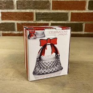 May include: A crystal ruby bell covered box with a red bow, 3 in x 2.6 cm, from the Celebrations by Mikasa collection.