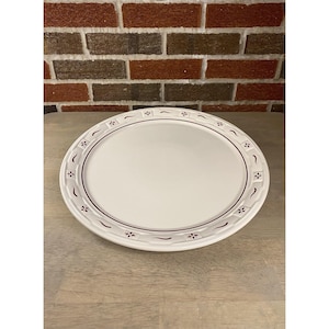 Könnte beinhalten: Ovale weiße Servierplatte mit einem bordeauxfarbenen Blumen- und geschwungenen Linienrand. Die Keramikplatte eignet sich zum Servieren von Speisen. Das Design ist schlicht und elegant.