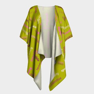 Può includere: Un kimono avvolgente color chartreuse con interno bianco. Il tessuto esterno è stampato con parole rosa e bianche, tra cui "efficienza", "innalzamento" e "supporto". L'indumento ha maniche larghe e un design fluido.
