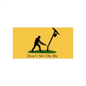 May include: A rectangular yellow flag featuring a black silhouette of a person using a saw to cut down a utility pole standing in a patch of green grass. The text DON'T SPY ON ME is printed in black capital letters at the bottom of the design.