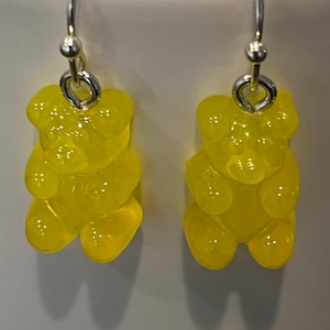 Könnte beinhalten: Ein Paar gelbe Gummibärchen-Ohrringe mit silbernen Haken.