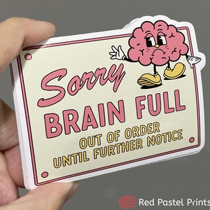 May include: A white sign with pink and yellow text that reads "Sorry Brain Full Out of Order Until Further Notice". A cartoon brain with a sad expression and arms and legs is at the top of the sign.