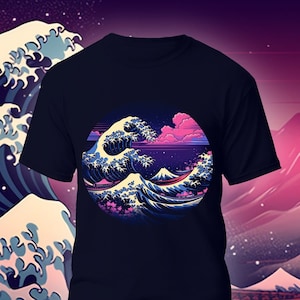 Puede incluir: Una camiseta negra con un gráfico de una ola azul y blanca con una montaña rosa en el fondo. El gráfico está en un círculo y tiene un estilo retro pixelado. La camiseta está sobre un fondo de un paisaje de montaña rosa y azul con flores de cerezo.