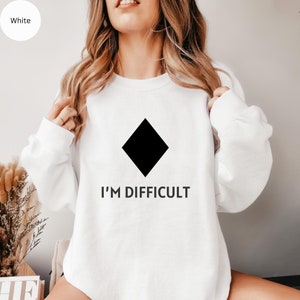 May include: White sweatshirt with a black diamond and the text "I'M DIFFICULT" printed on the front.