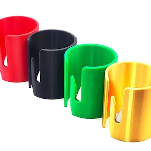 May include: Four colorful tape dispensers in red, black, green, and yellow. Each dispenser is a cylindrical shape with a curved slot for tape dispensing. The dispensers are arranged in a row against a white background.