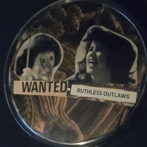 May include: A circular pinback button featuring a collage of two black and white portraits of people with expressive faces. The text WANTED and RUTHLESS OUTLAWS is printed on white rectangular strips layered over the images against a dark background.