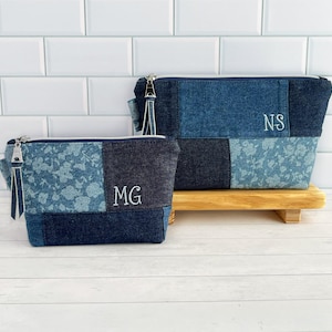 May include: Two denim makeup bags with floral patterns and personalized initials. The larger bag has the initials "NS" and the smaller bag has the initials "MG".