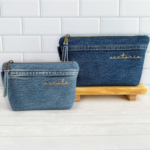 May include: Two denim cosmetic bags with gold embroidery. The larger bag says "Victoria" and the smaller bag says "Nicole".