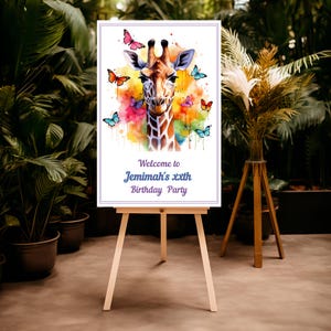 Puede incluir: Un letrero blanco sobre un caballete de madera presenta una jirafa de acuarela con mariposas de colores. El letrero dice "Welcome to Jemimah's xxth Birthday Party" en púrpura. El fondo incluye plantas verdes.