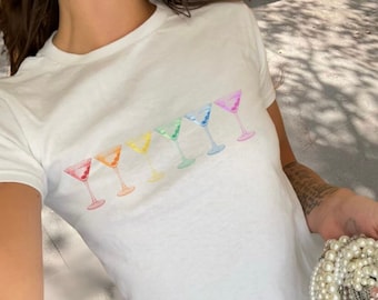 May include: White t-shirt with a rainbow design of martini glasses.