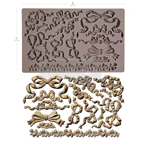 Puede incluir: Un molde de silicona gris con varios diseños de lazos y cintas, que mide 20,3 cm por 12,7 cm. Debajo, una exhibición de lazos y cintas dorados, mostrando el producto final potencial. El molde incluye detalles florales.
