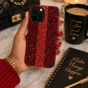 May include: A smartphone case featuring a vibrant, deep red glitter finish with a textured, sparkling surface. The case has a precise cutout for a triple-lens camera system on the back, showcasing a bold, reflective appearance that catches the light.