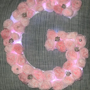 Letra de madera cubierta de flores iluminadas