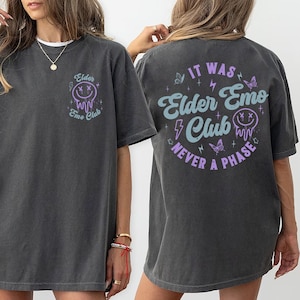 May include: An oversized dark grey t-shirt with a purple and blue graphic on the front that says "Elder Emo Club" and a purple and blue graphic on the back that says "It Was Elder Emo Club Never A Phase".